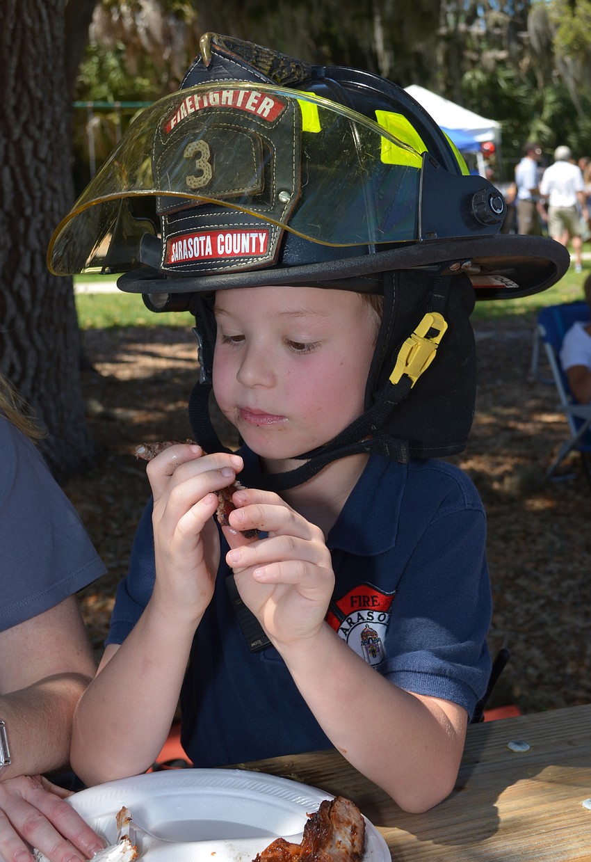 Wearing his father’s helmet, Jake Bolds samples ribs.