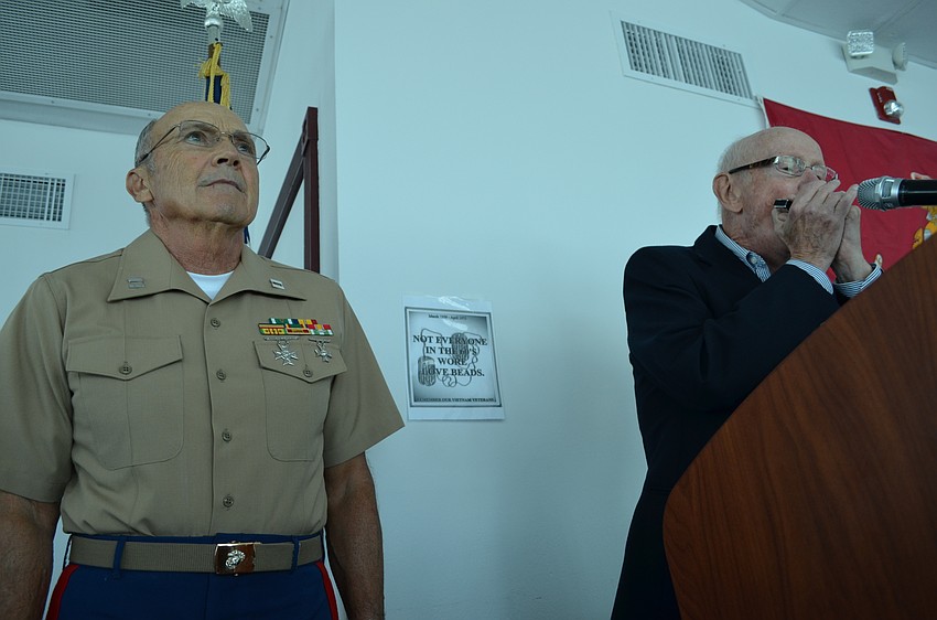 Tom Smith stands at attention while Peter Minotti plays the harmonic during a moment of silence.