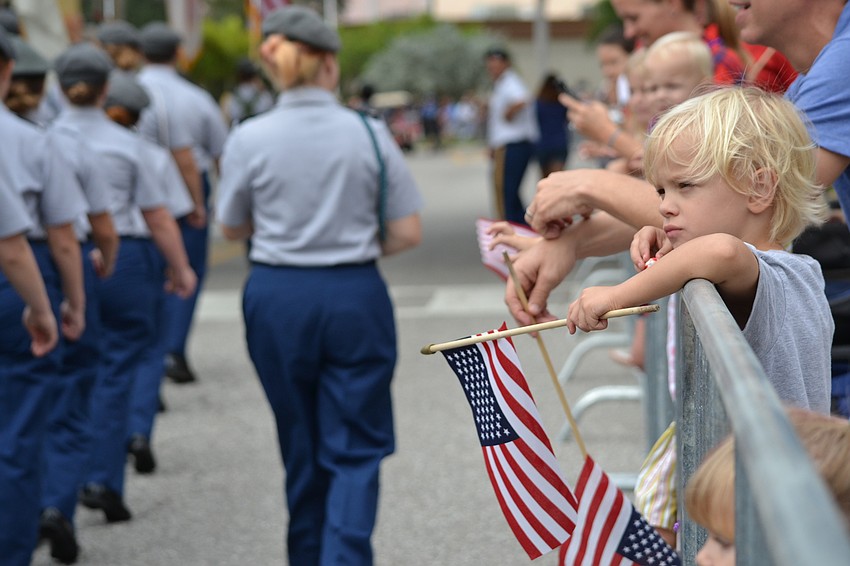 Cash Woods hangs over the barricade to wave his flag at Sarasota Military Academy cadets.
