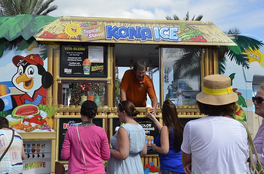 Kona Ice owner Dave Boyers passes down shaved ice cups to Empty Bowls attendees.