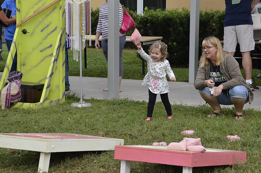 Emerson Otto gives cornhole a try with help from Julie Terwilliger, a pre-kindergarten teacher.