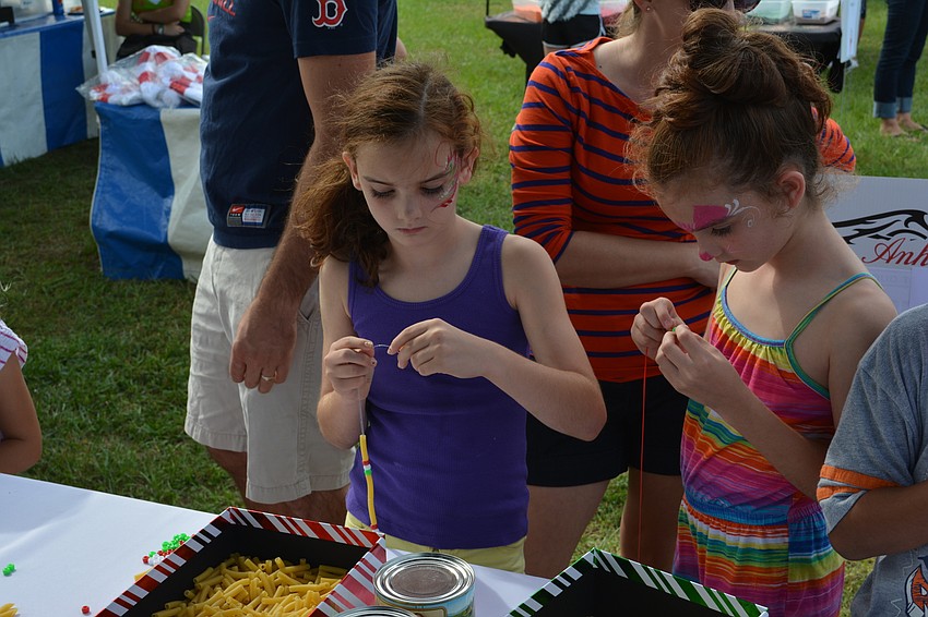 Lakewood Ranch's Claire and Brooke Danley, who are twins, build pasta necklaces on Saturday during Festa Italiana.
