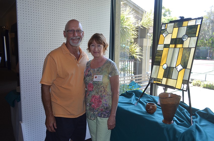 Wood artist Eric Stackowicz and wife, stained glass artist Rosemary, pose in front of their work.