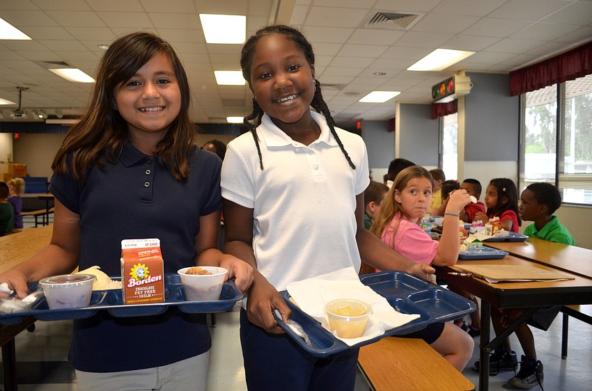 Nine-year-olds Ariana Garcia and Ovonya Pinder find a seat to enjoy their Thanksgiving lunch.