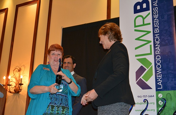 One of a Kind winner Janet Arena of Van Wezel Performing Arts Hall walks to the stage to accept her award from Manatee County Commissioner Betsy Benac.