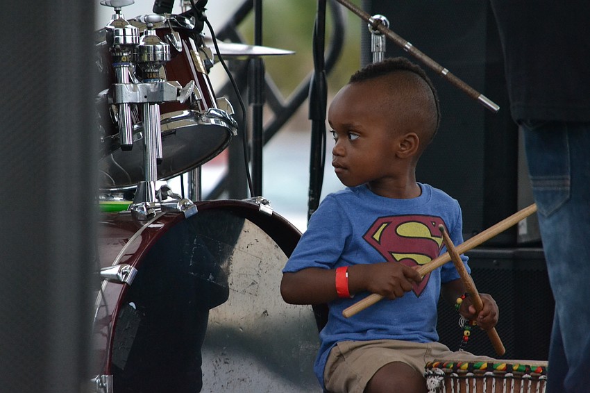 Three-year-old Kymani Caines looks back at the drummer during a performance with Jah Movement.