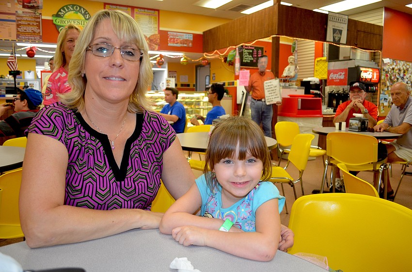 Tammy Cross and Aubrey Jenkins, of Bradenton, hide from the rain inside Mixon's shop.