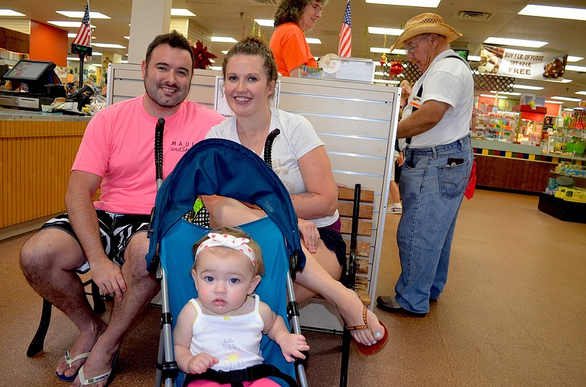 The Ennis family — Steve, Dominique and Kameron — find dry shelter after an afternoon rain shower.