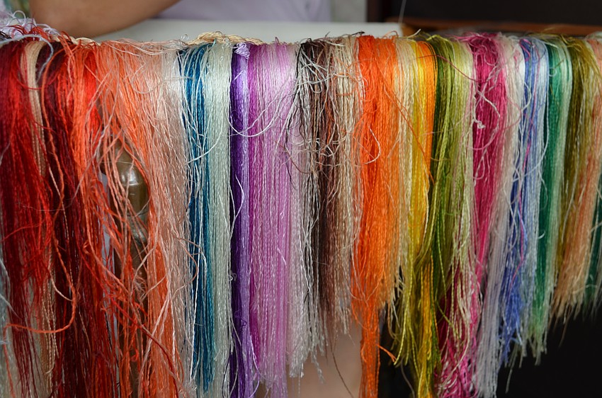 Threads hang off the edge of Xiao Xia Zhang's work surface as she embroiders her next work of art.