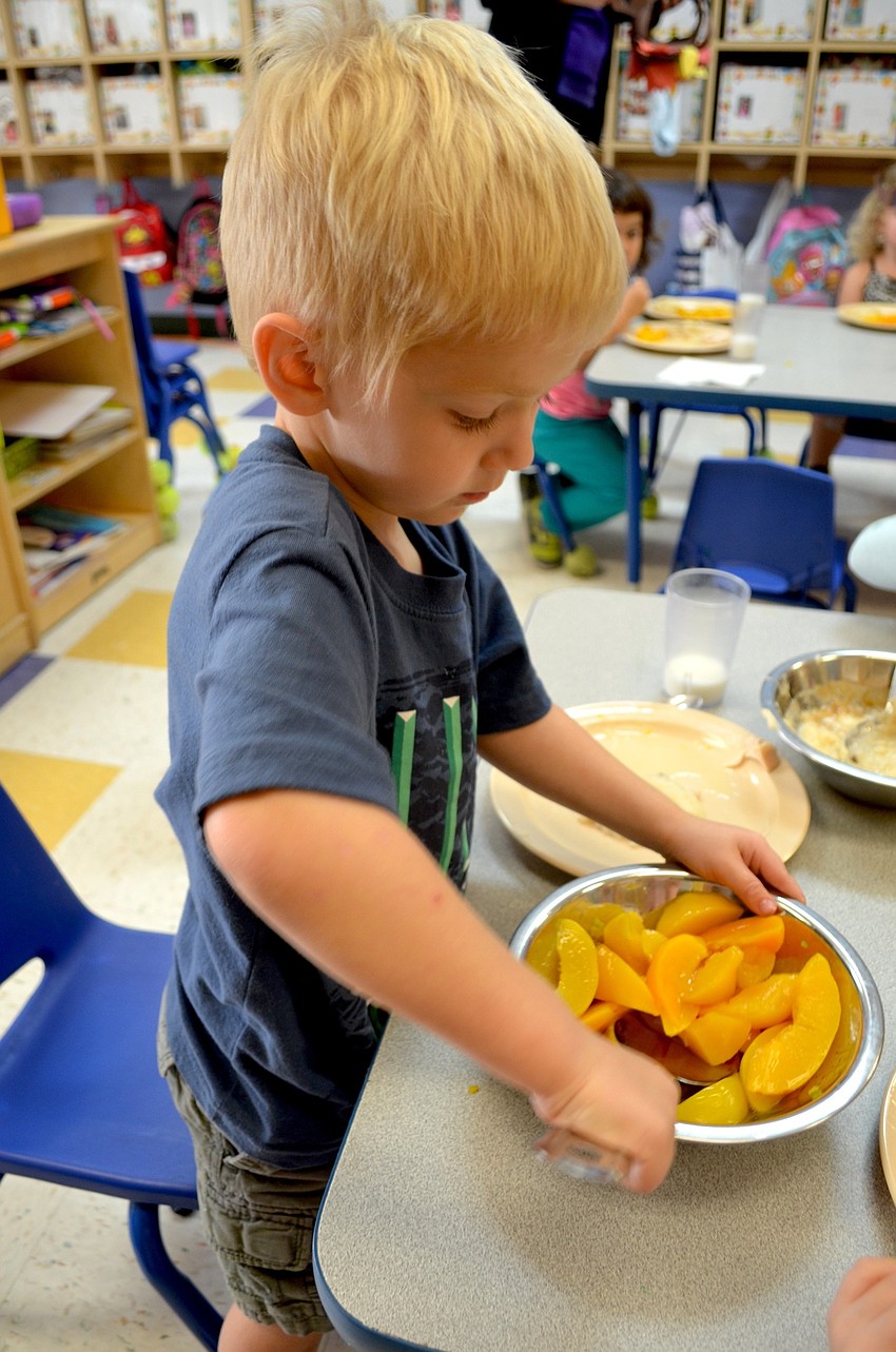Three-year-old Michael Kildow loves peaches and helps himself to a third serving.