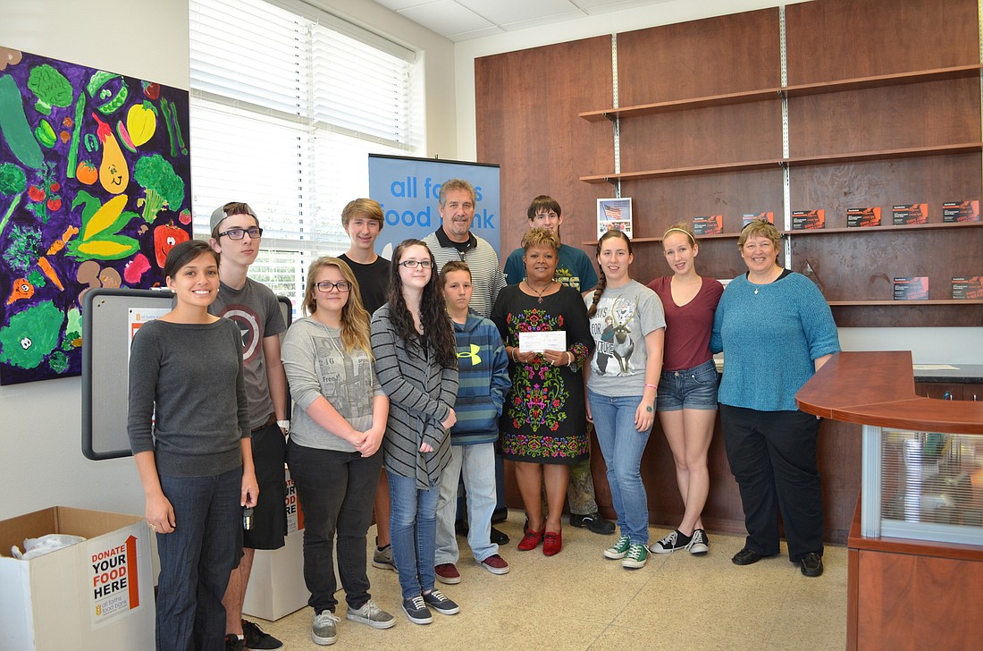 Pine Shores Presbyterian Church youth group members present the $19,256 check to All Faiths Food Bank Chief Operating Officer John Livingston and Director of Donor Relations Aundria Castleberry.