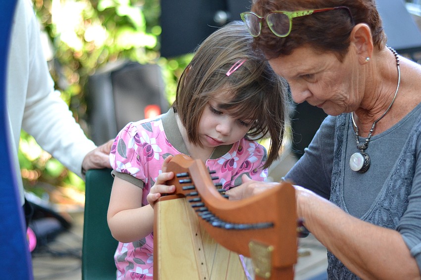 Norah Ceaser and Mary Pickup pluck the strings on a harp.
