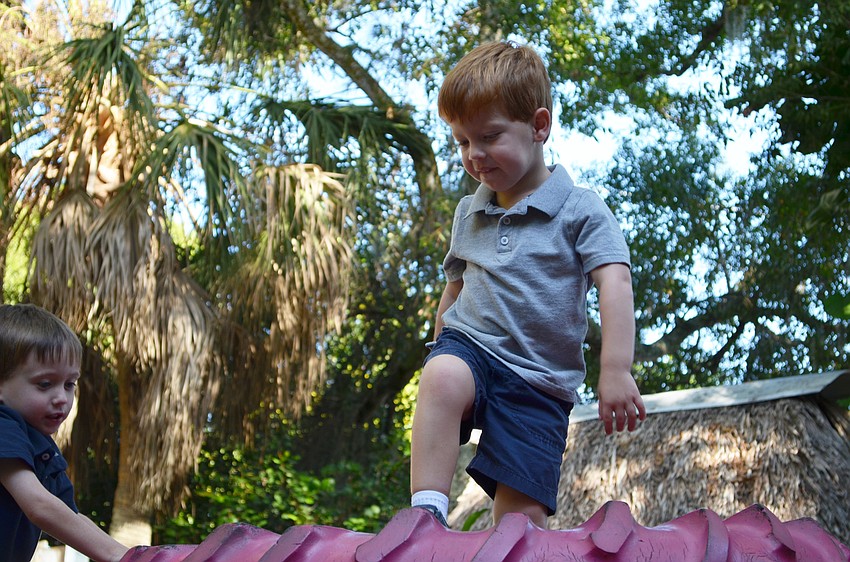 Twins Bennett and William Silverstein climb the tire mountain at the Sarasota Children's Garden.