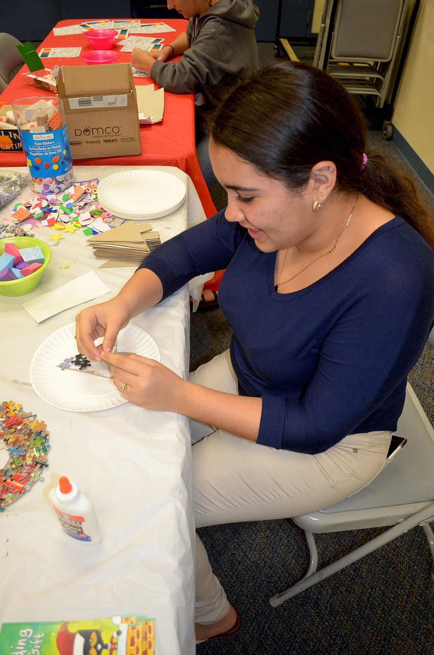 Amanda Hernandez, of Bradenton, volunteers to help children make holiday-themed crafts.