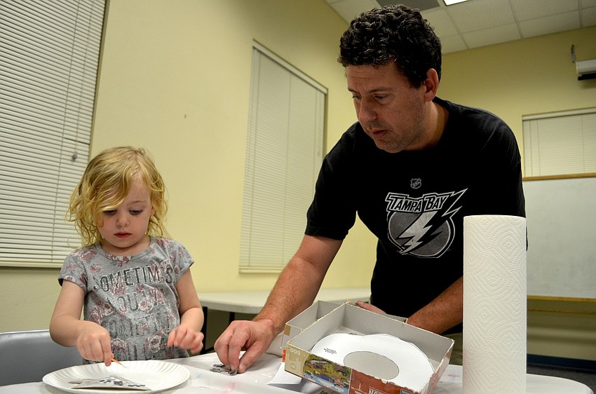 Sophia Tabb, of Bradenton, works with her father, Steve, to decorate a cardboard tree.