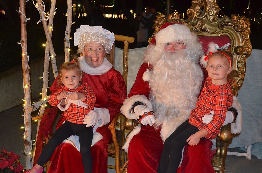 Brooke Messenger, 2, and sister, Nichole, 4, sit on Mrs. Claus and Santa’s laps.