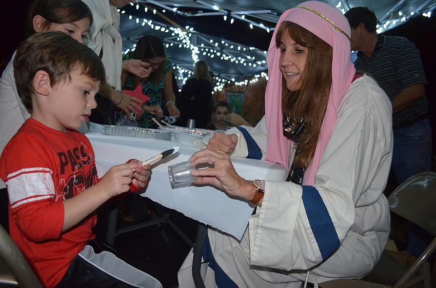 Ben Byrnes, of Bradenton, paints a glass with the help of event volunteer, Lori Norgart.