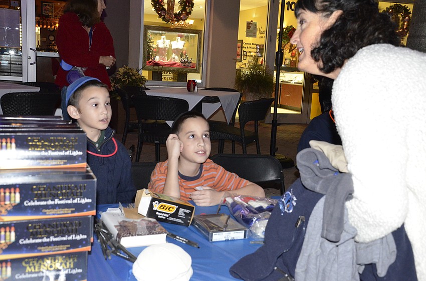 Shaya and Mordechai Bukiet talk with Rhonda Lee of GreyHawk Landing about the menorahs for sale.