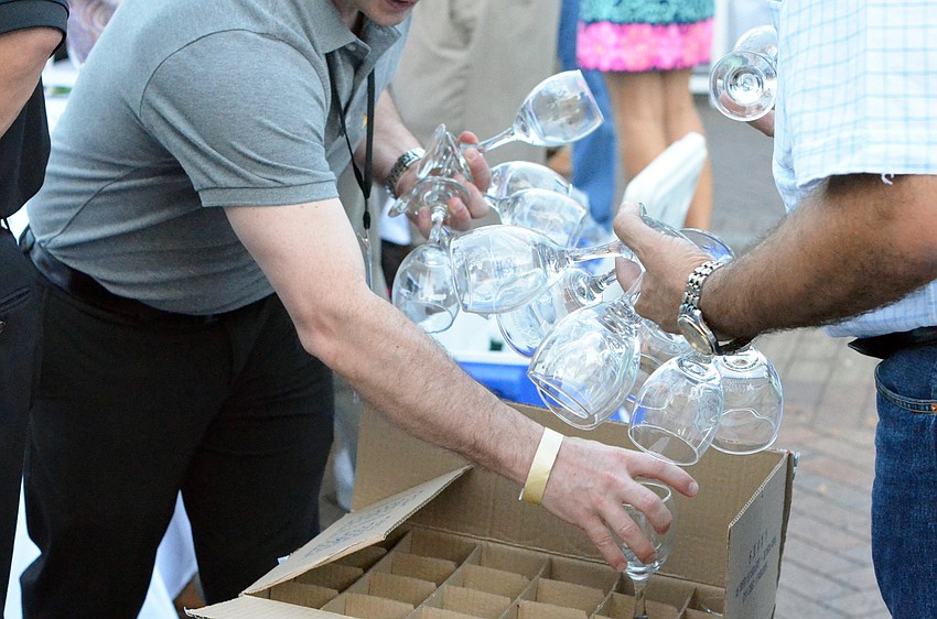 Vintners restock their tables with wine glasses during the wine tasting.
