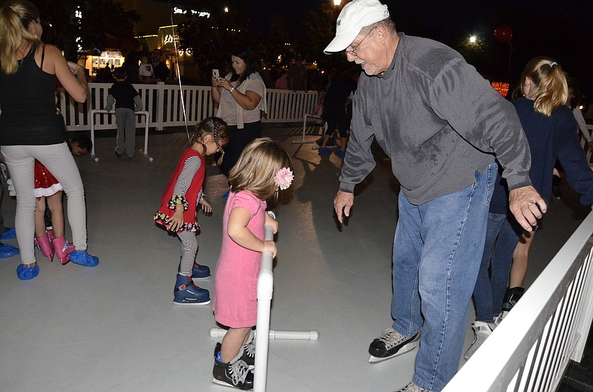 Bruce Baldwin, an event volunteer, helps Chloe Rowe of Lakewood Ranch cruise around the 
