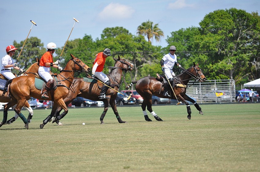 Polo players race for the ball.