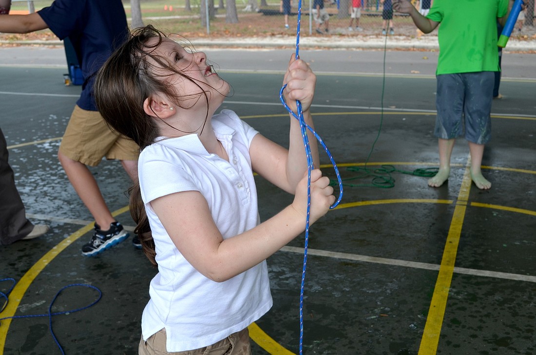 Kindergartener Ryelynn Brunner maneuvers the slime bucket to dump on Assistant Principal Samantha Webb.