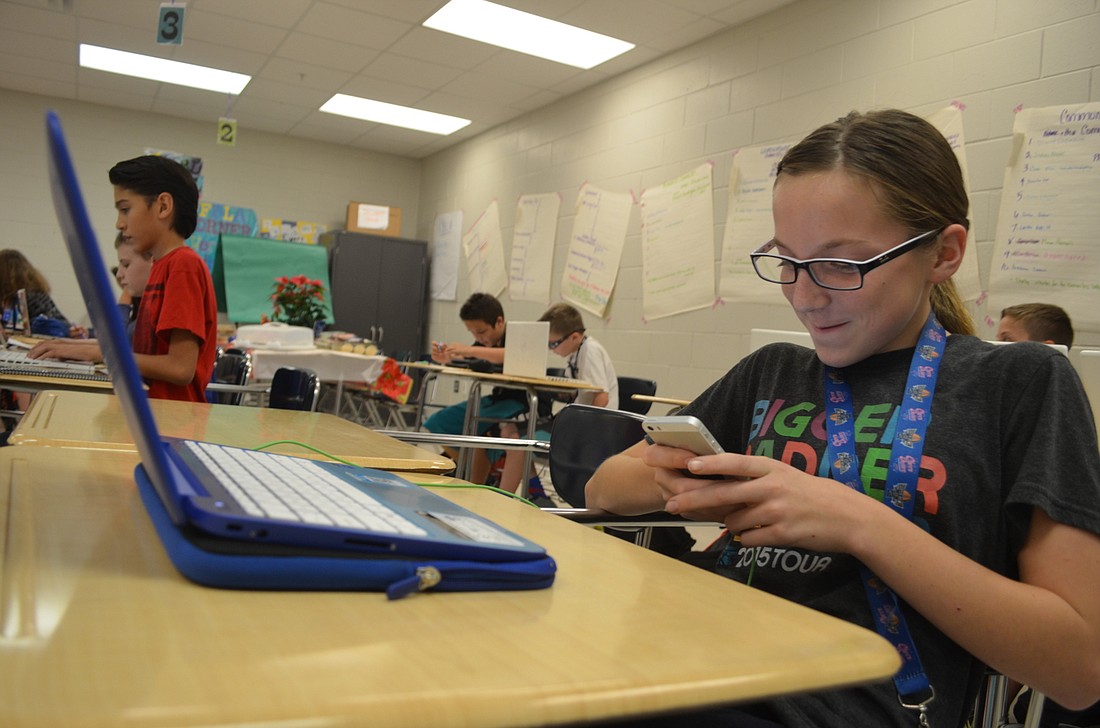 Kayla Morris uses her iPhone and laptop during class at Nolan Middle.