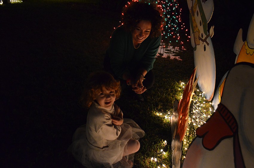 Mindy Rollins and her daughter Eve try to keep warm near a cutout of a campfire.