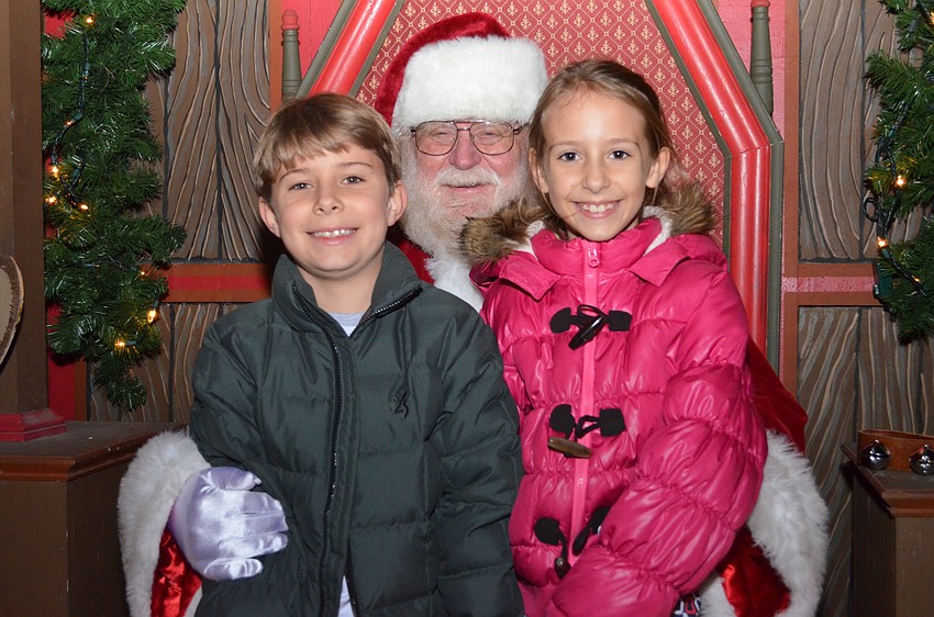 Siblings Sam and Camille Wright sit with Santa Claus.