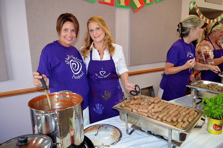 Event volunteers Andrea West and Valeria Sthreshley serve up hot sausage and sauce to patrons.