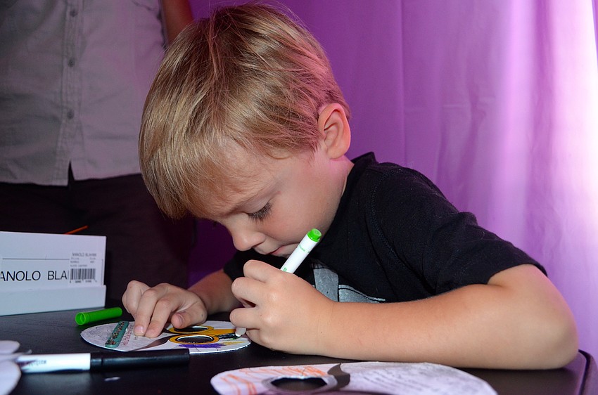Four-year-old Logan Cole colors a paper mask he'll wear later.