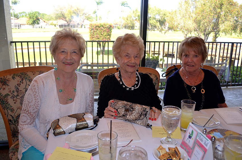 Joan Ackerman and Barb Wilson show off their clutch purses beside their friend, Fran King.