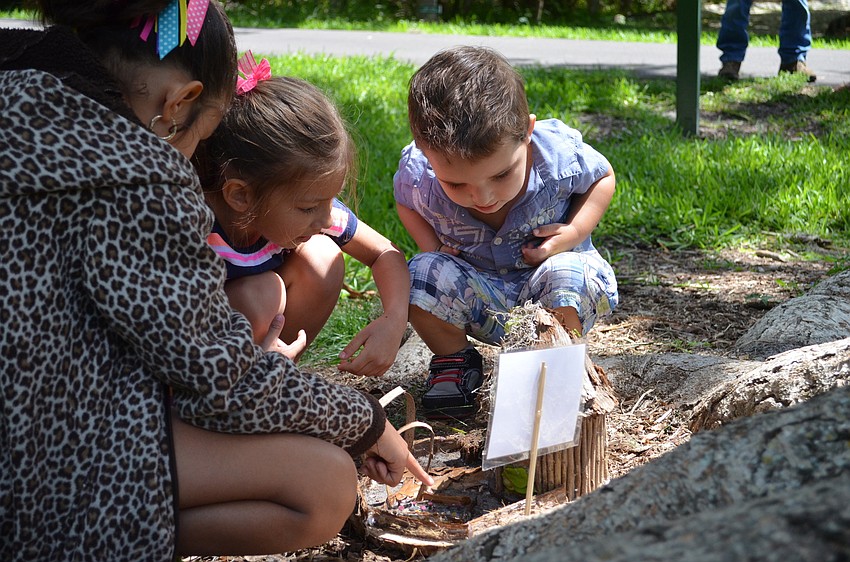 Ashley and Olivia Chinchilla with Josiah Frapiccini get a closer look at a fairy house nestled at the base of a tree.