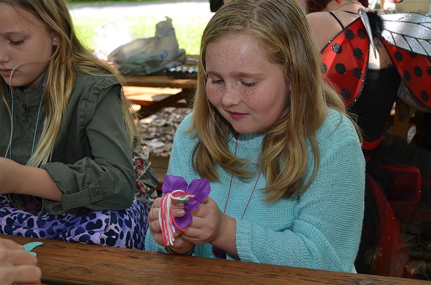 Ella Queen makes a fairy out of a pipe cleaner and yarn.