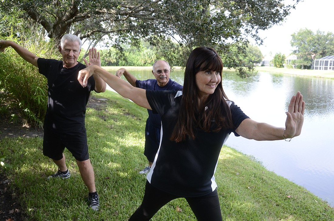 Ian Black and Jim Soda, led by instructor Rosann Argenti, hold the single whip push pose.