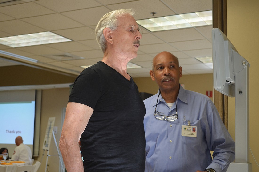 Pines of Sarasota Lead Physical Therapist James McClure, right, helps Dickie Smothers try out the Biodex Balance System.