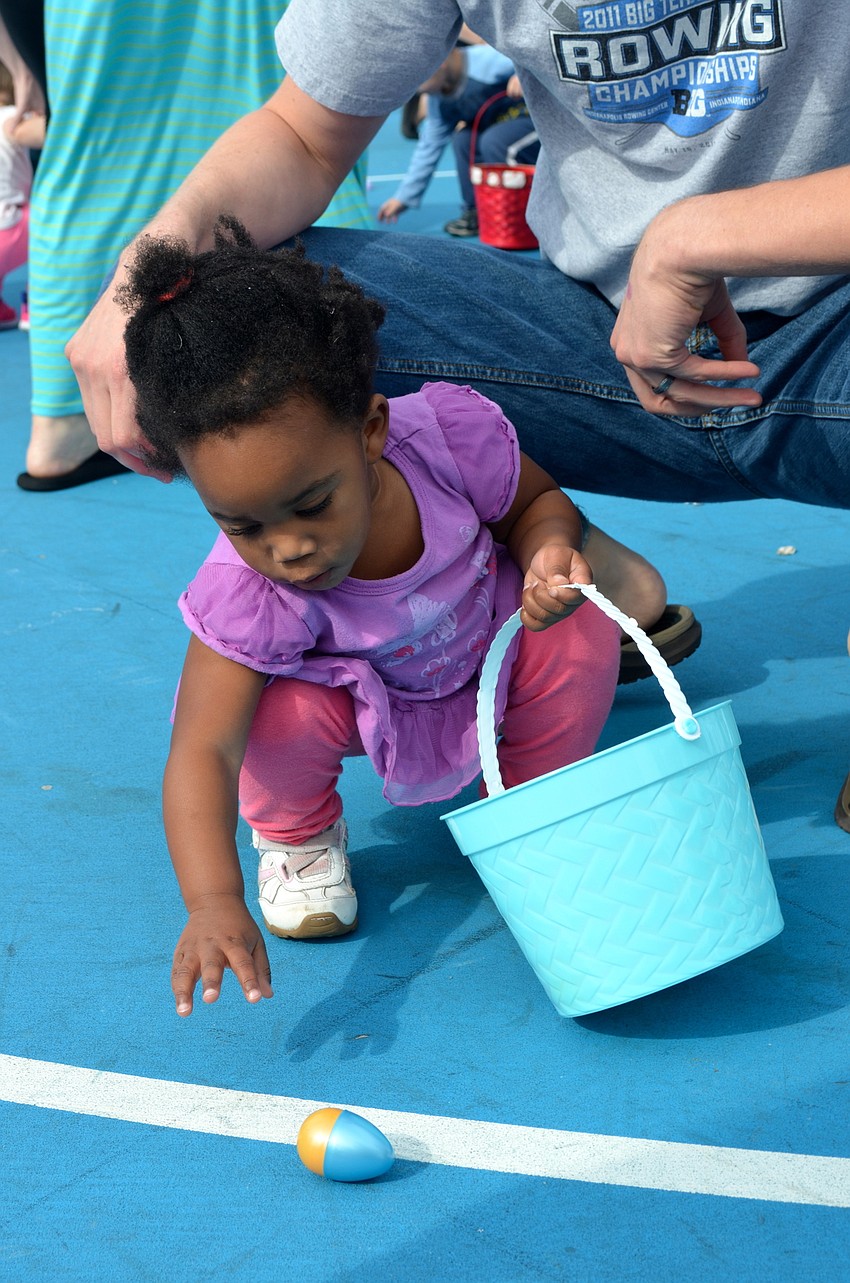 Two-year-old Tayla Jordan quickly gathers as many eggs as her little hands can hold.