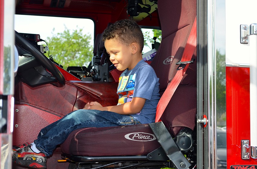 Three-year-old Graham Williams plays fireman inside a truck belonging to the Manatee Fire and Rescue team.