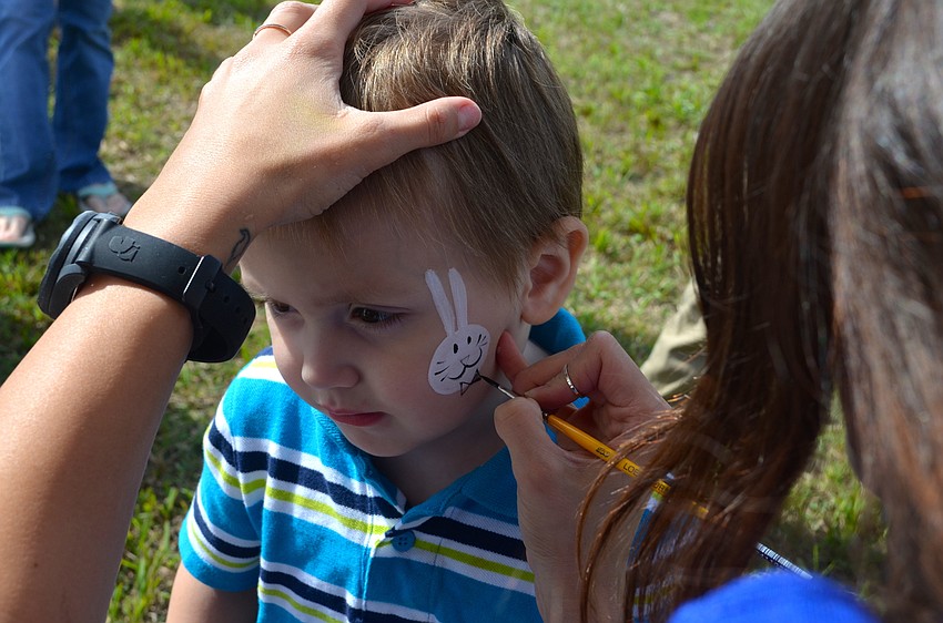Ridgeland McMillan, 2, patiently waits while his Easter Bunny face paint is drawn.
