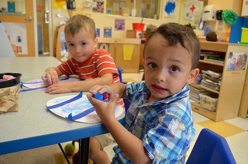 Three-year-olds Mason Polley and Domenick Garcia decorate paper Easter eggs to give to their mothers.
