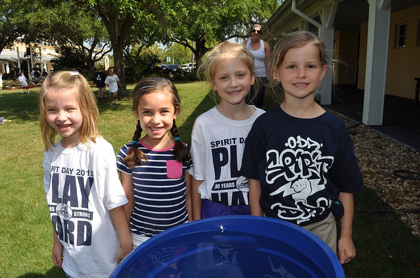 Grace, Lillian, Madeleine and Avary play with a bucket of water in the shade.