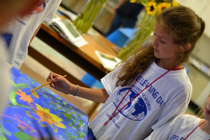 Sophia Miller adds brushstrokes to the third grade painting in the Europe section.