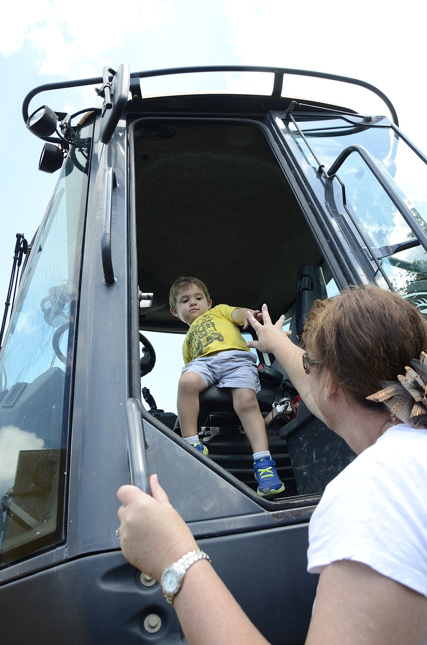 Colton Barnett, 2, gets help out of a tractor from Polly Barnett, his grandmother. Polly said he loves big trucks–he had on a Tonka truck t-shirt.