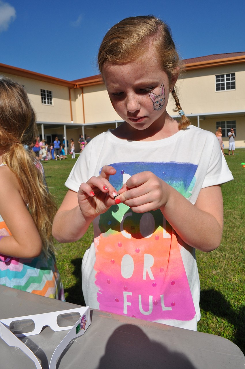 Meredith Beck, 8, decorates a pair of paper glasses.