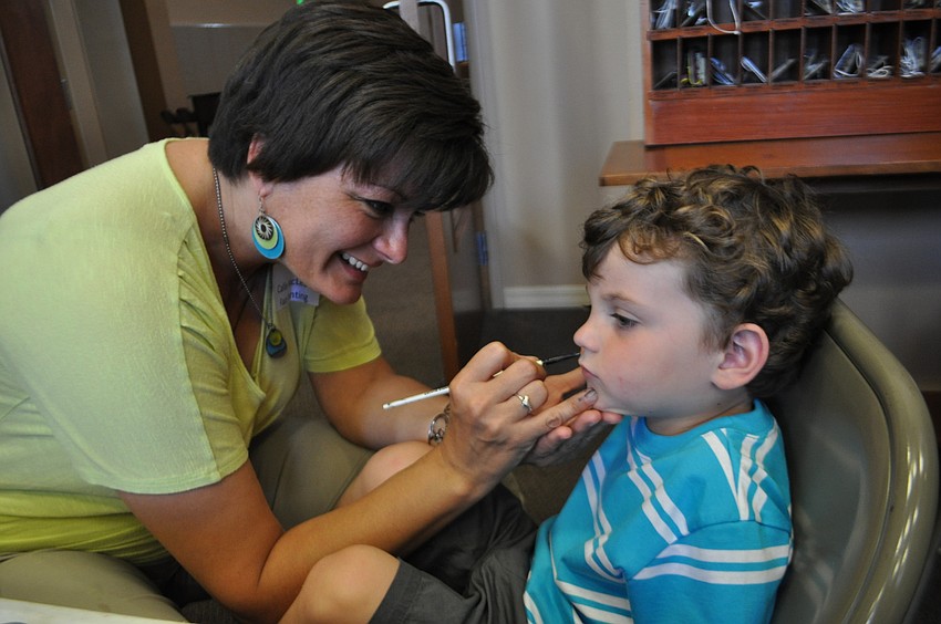 Callie MacLeod paints a sun on the face of 2-year-old Hayden Laning.
