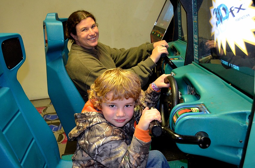 Blaine Smith shows his mother, Michelle, how to race cars in an arcade game.