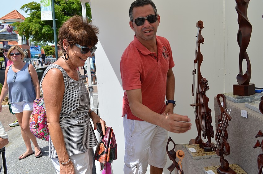 Claire Verdi admires a wooden sculpture by Osmany Sarquiz.
