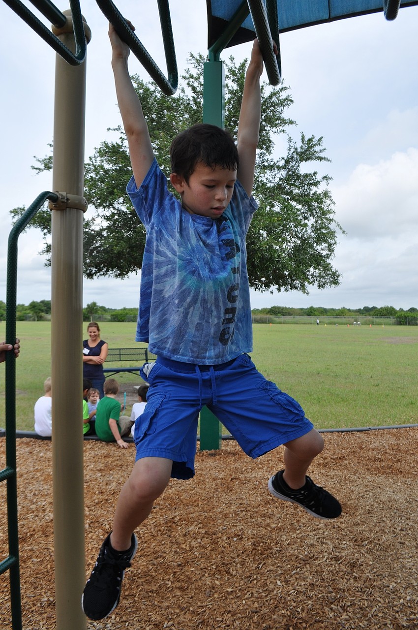 Aidan Hall, 7, tests his skills on the monkey bars.