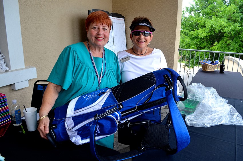 Janet Arena and Barbara Zdziarski show off one of the day’s prizes — a bag filled with golf equipment.