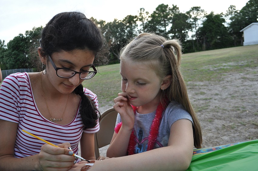 Braden River Middle School student Winoma Nasser paints a dog on the hand of Sariah Frymier, 6.